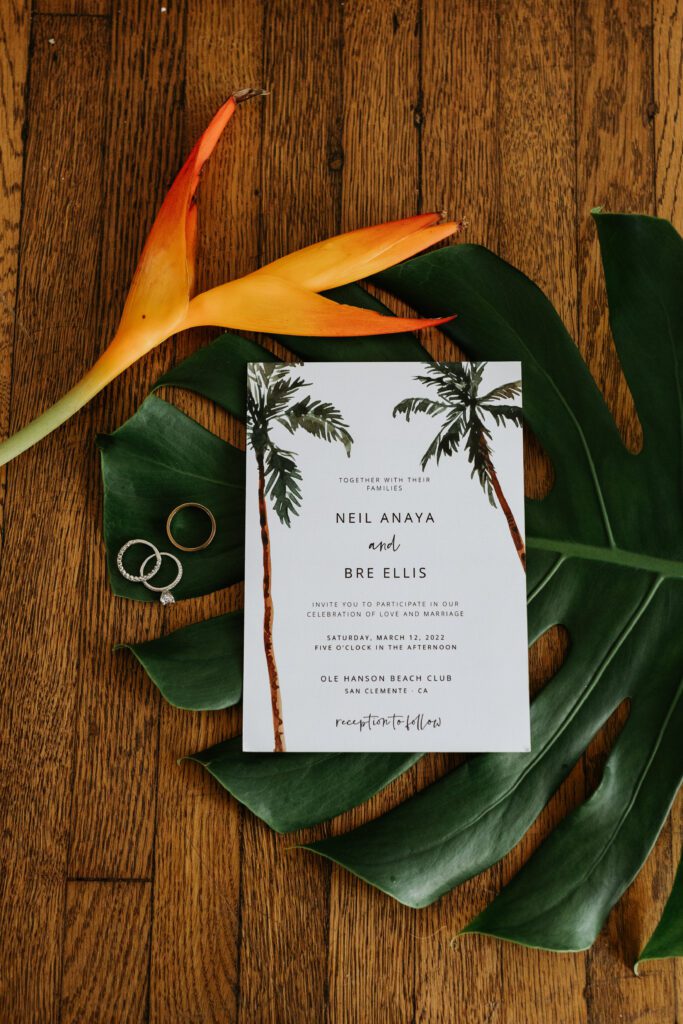Flat lay with invitation, rings, and tropical flowers