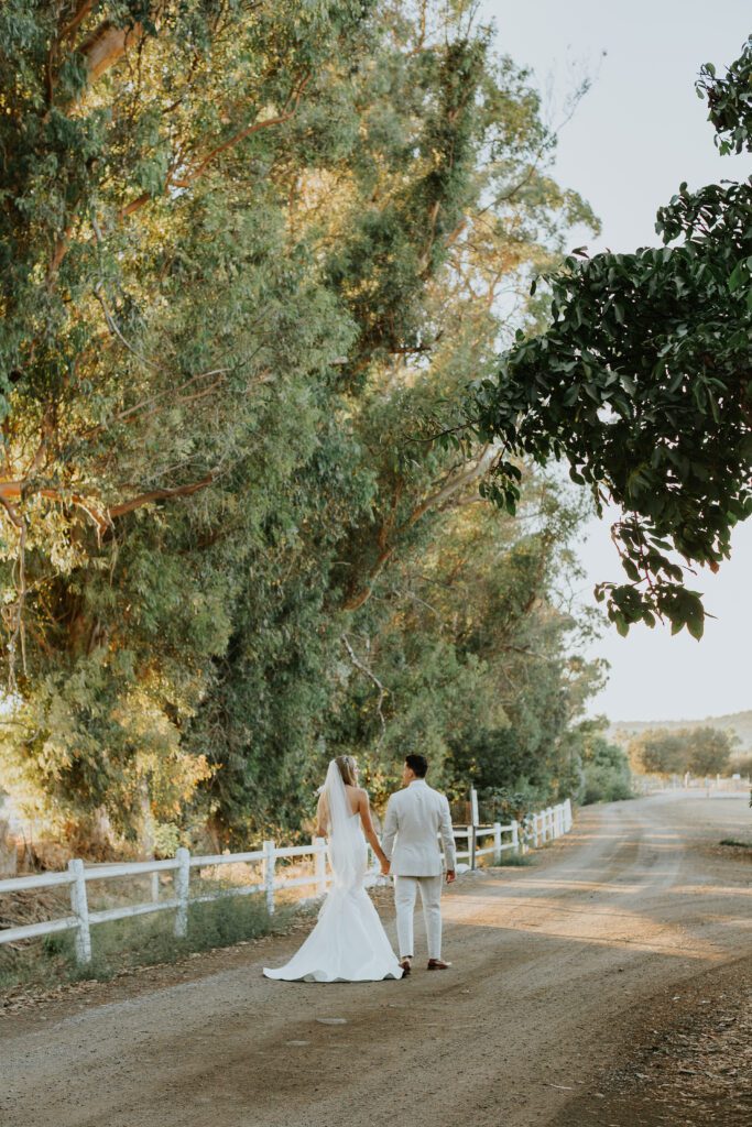 Couple walking down a dirt road at a beautiful outdoor wedding venue