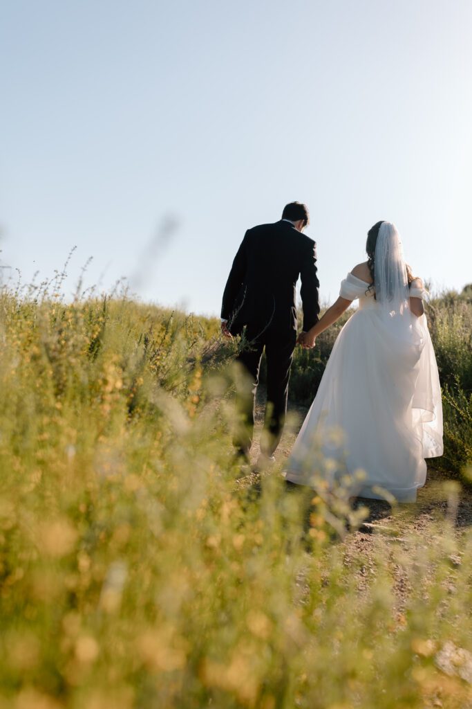 Bride and groom walking through wildflowers in Southern California